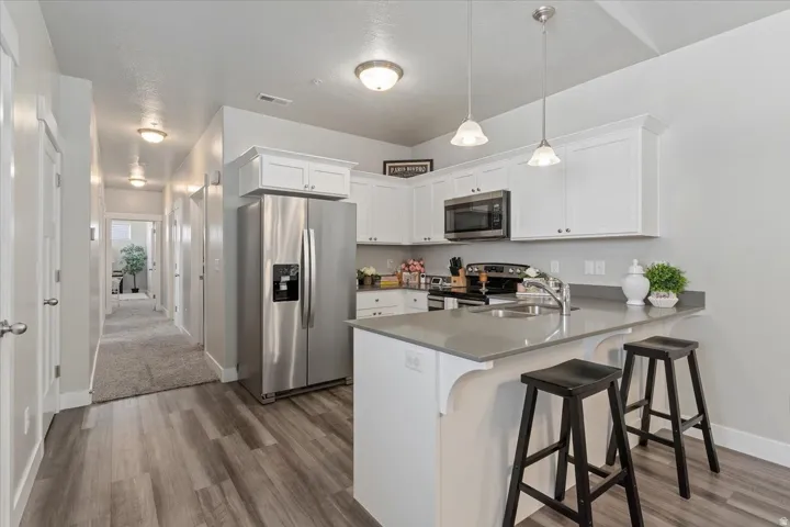 Kitchen featuring white cabinetry, stainless steel appliances, a breakfast bar, and pendant lighting