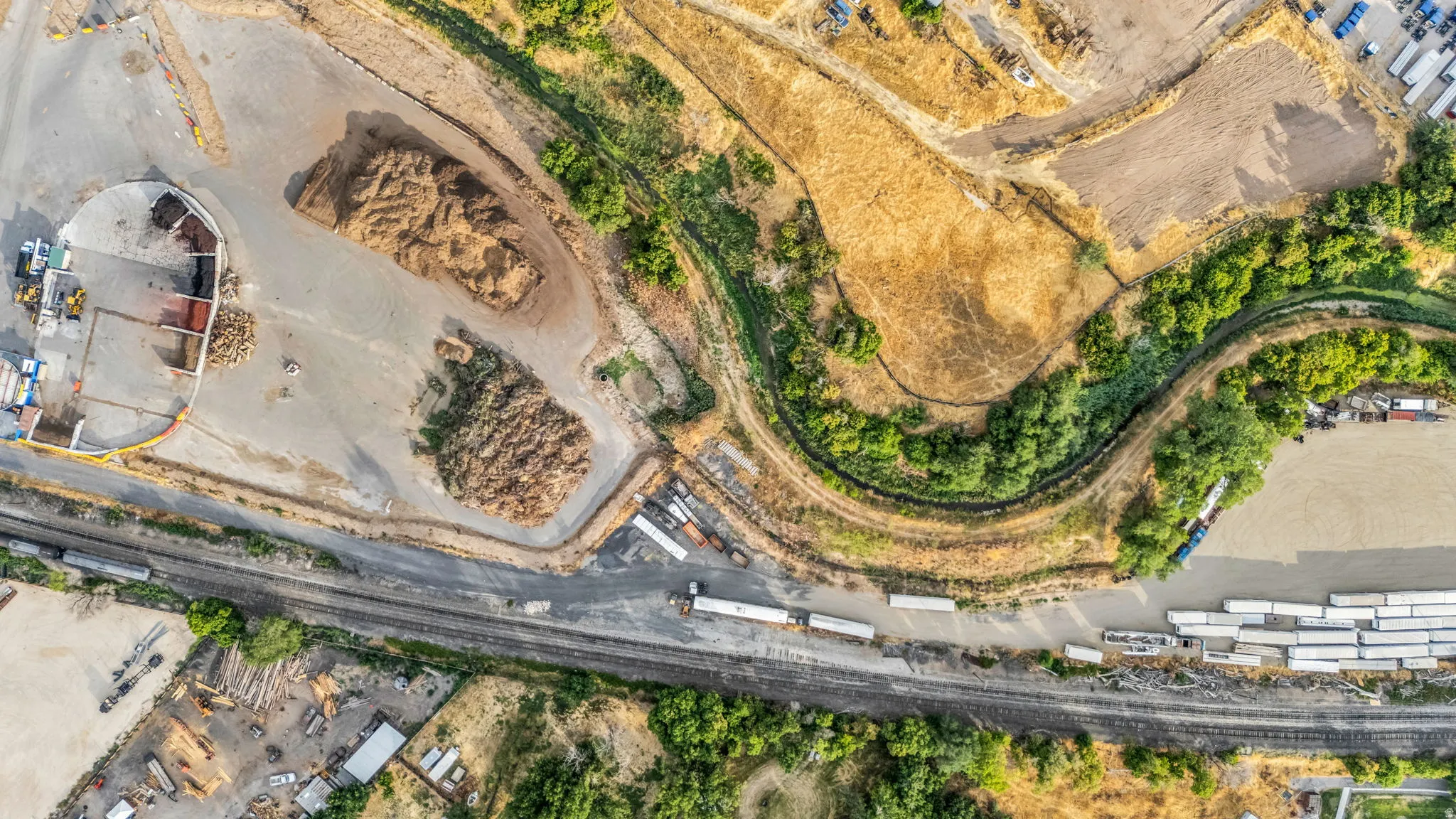 Industrial property featuring multiple gravel lots, railroad access, and proximity to natural green space