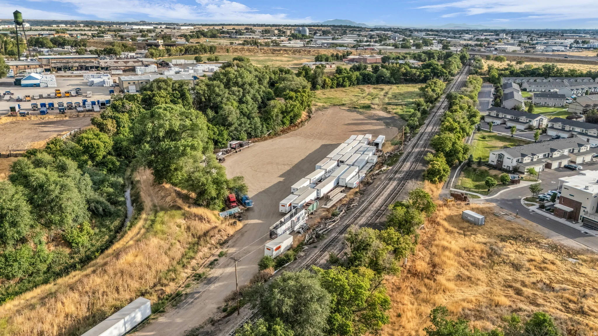Open land parcel with adjacent railroad tracks and a tree-lined perimeter