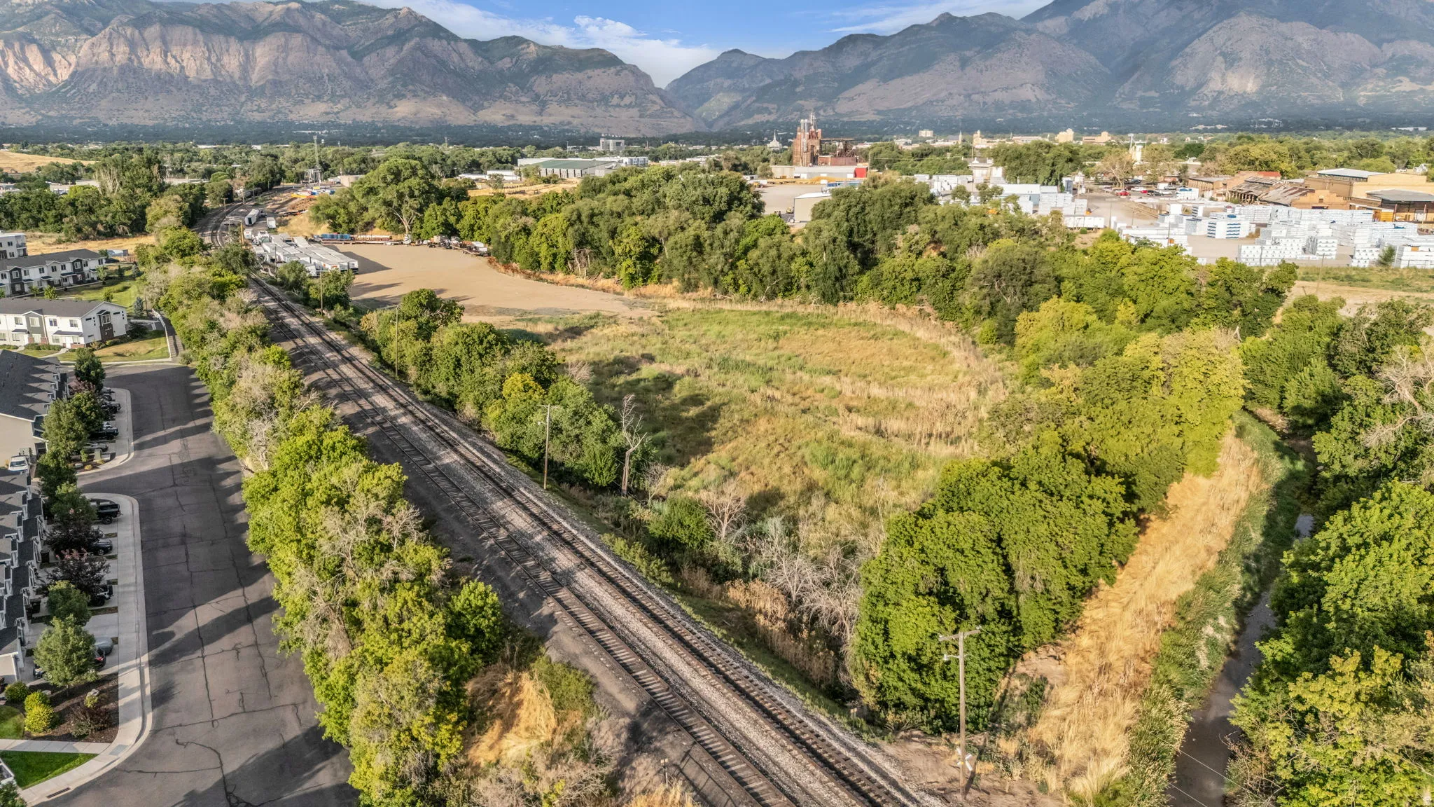 Expansive open land with surrounding mature trees and a distant mountain backdrop