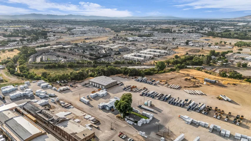 Expansive commercial property featuring multiple industrial structures, open storage areas, and vehicle parking