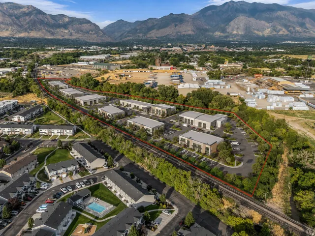 Aerial perspective showcasing multiple commercial buildings with ample parking, surrounded by green landscaping and mature trees