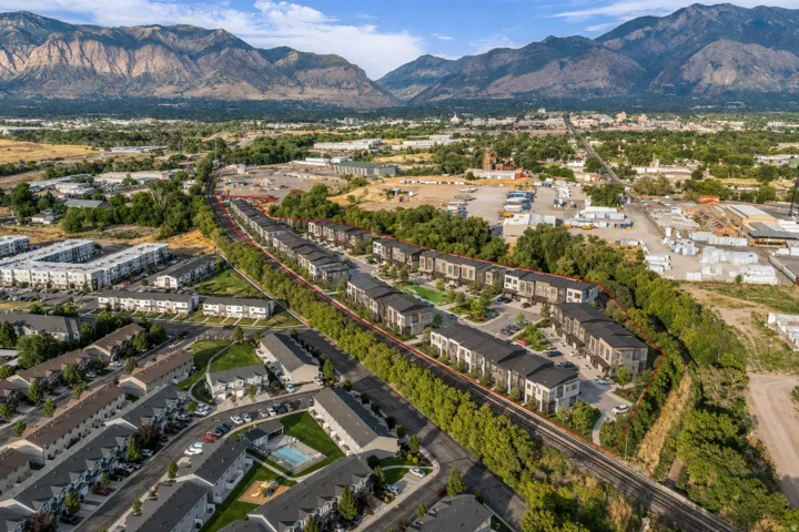 Mountain backdrop, residential area, multiple buildings with varied architectural styles, green landscaping, paved roadways