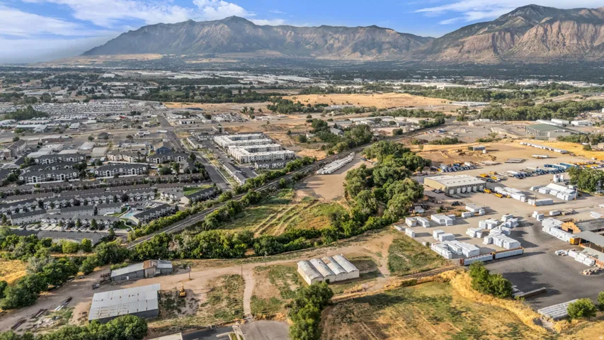 Expansive aerial capturing a broad landscape with distant mountains, commercial structures, and residential development
