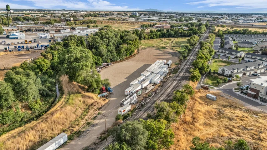 Open land parcel with adjacent railroad tracks and a tree-lined perimeter