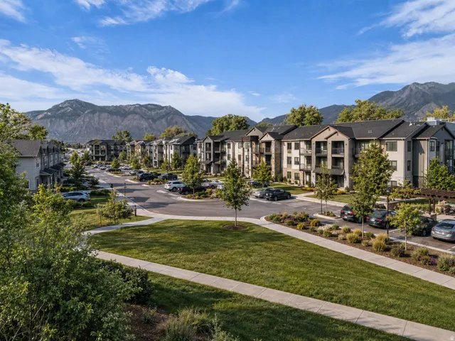 Modern apartment buildings featuring balconies and a surrounding landscape with trees and grass