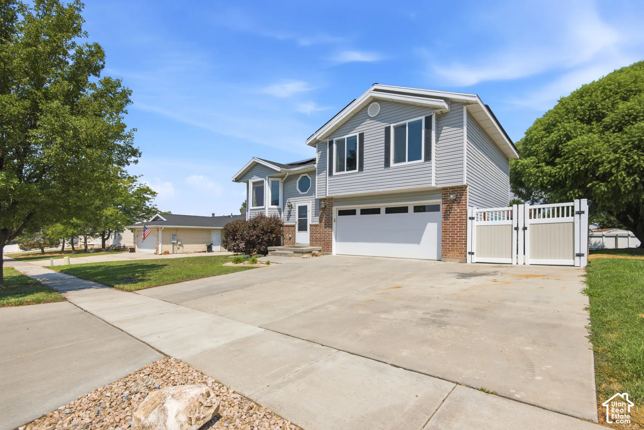 Two-story residence featuring light gray siding with brick accents and a two-car garage