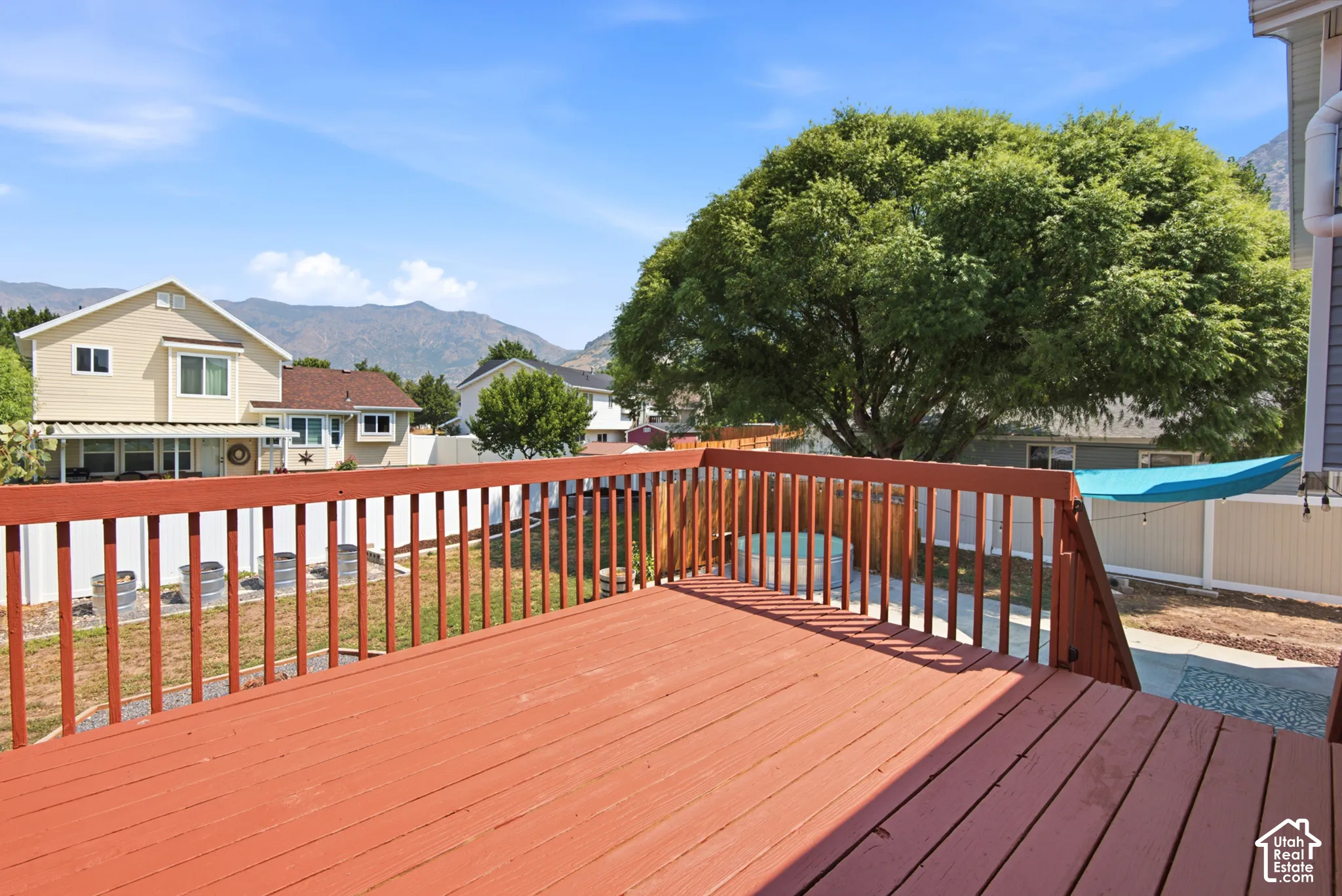 Expansive red-stained wood deck with a full railing, overlooking a partially fenced yard