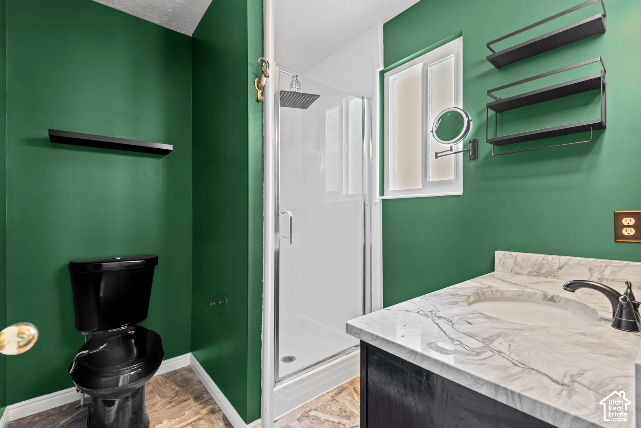 Bathroom featuring a glass-enclosed shower, rain showerhead, white countertop with integral sink, black vanity, and black fixtures