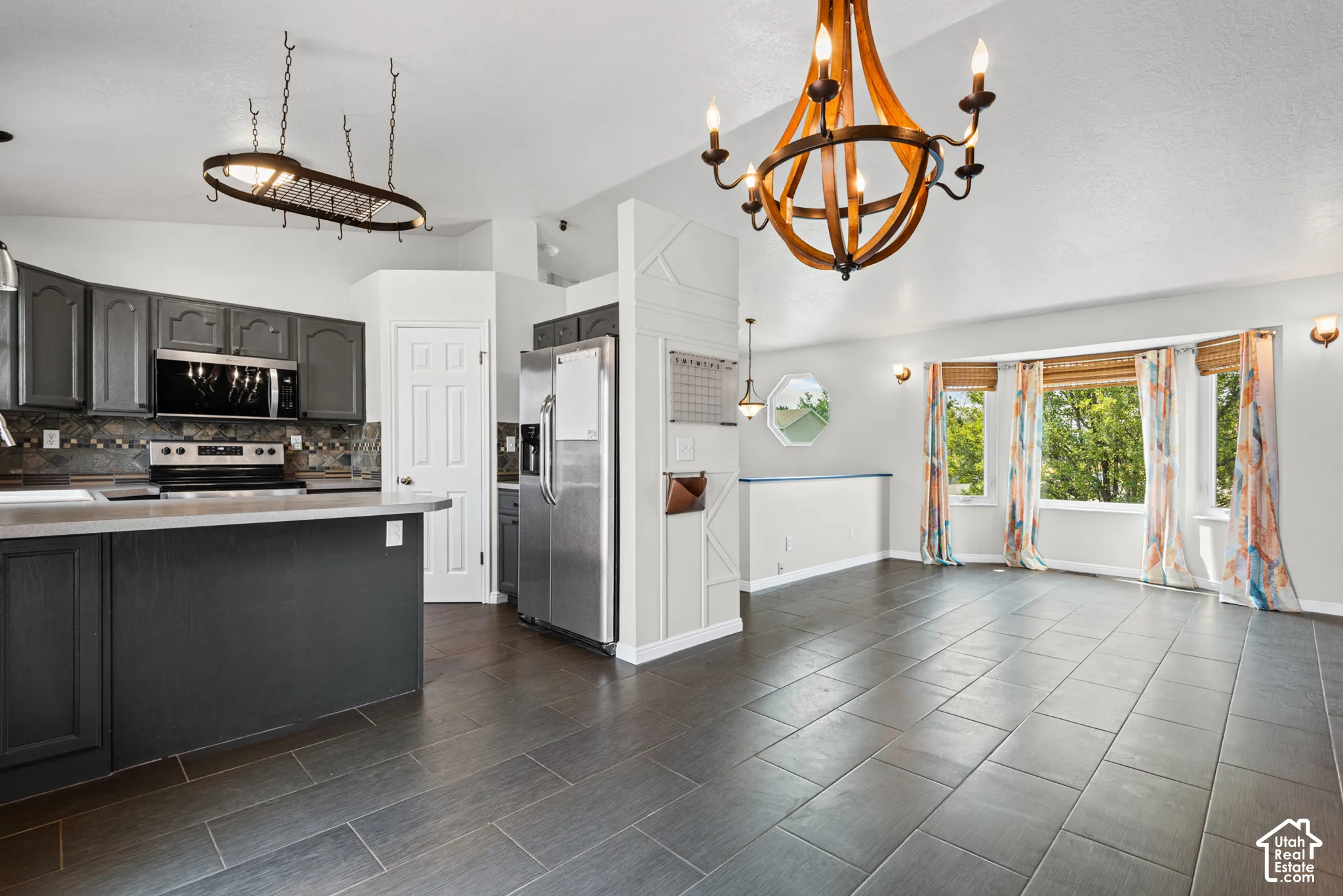 Open-concept living space featuring a kitchen island, stainless steel appliances, vaulted ceiling, and bay windows