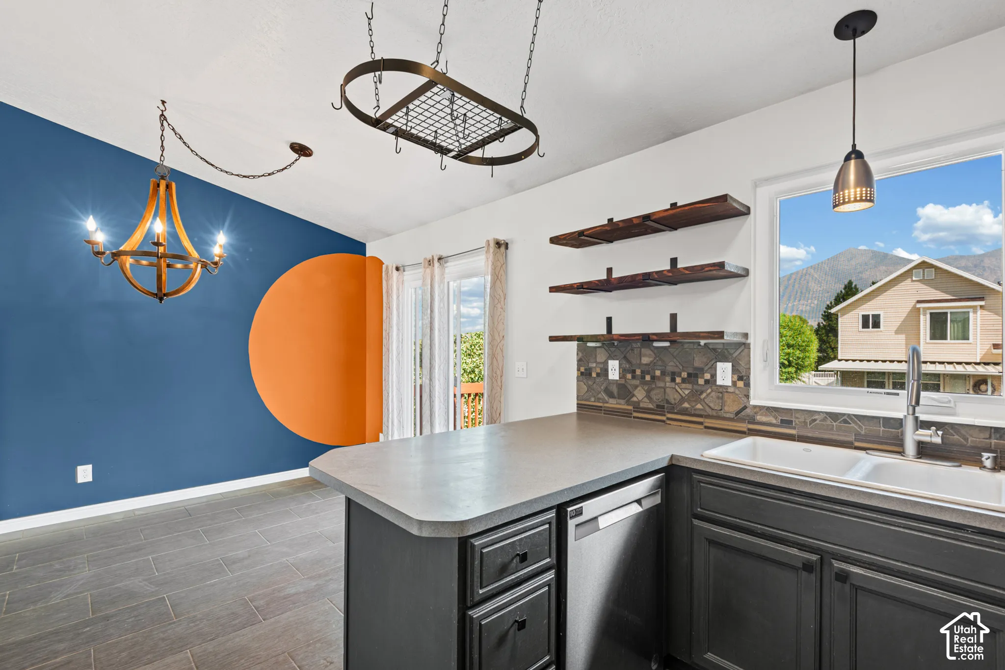 Kitchen featuring a double basin sink, dark cabinetry, and contrasting stone backsplash