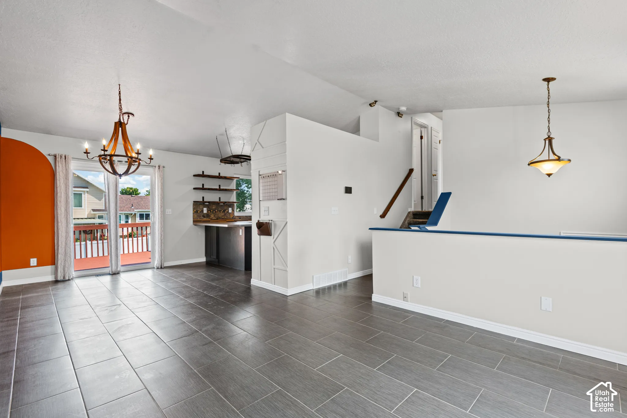 Wood-finish tile flooring throughout, with a built-in wet bar featuring open shelving and a tile backsplash
