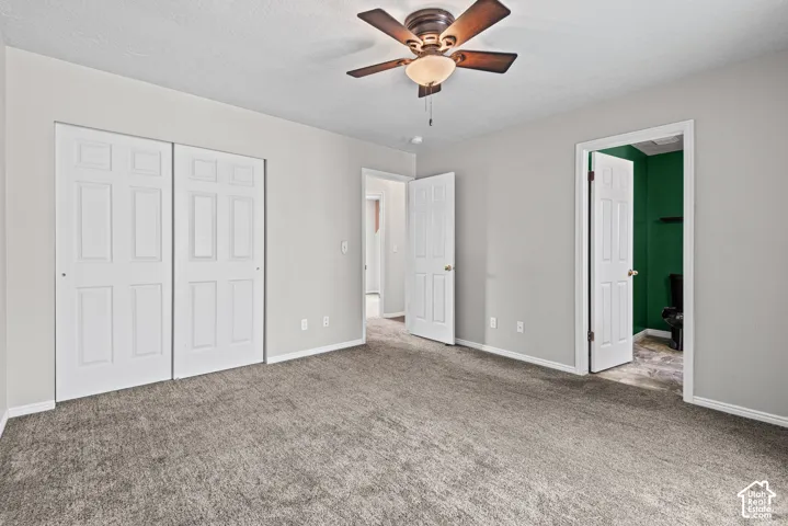 Neutral tone walls, ceiling fan with light fixture, textured carpet, and panel doors