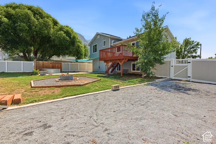 Gravel parking area, fenced backyard, raised wood deck, ground-level patio, and a fire pit feature