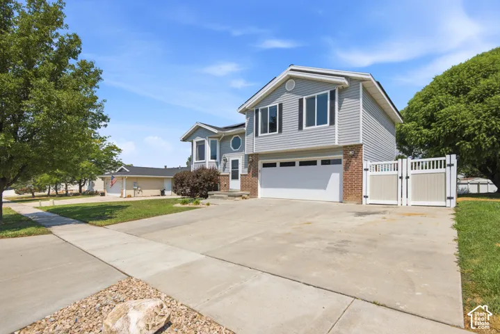 Two-story residence featuring light gray siding with brick accents and a two-car garage