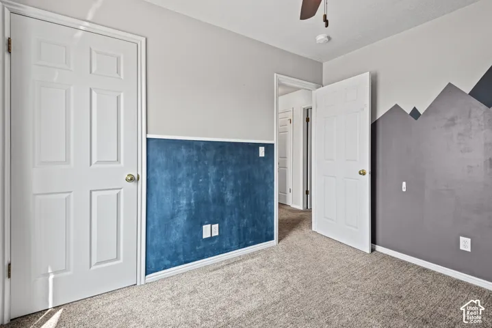 Plush carpet flooring, ceiling fan, and painted panel doors
