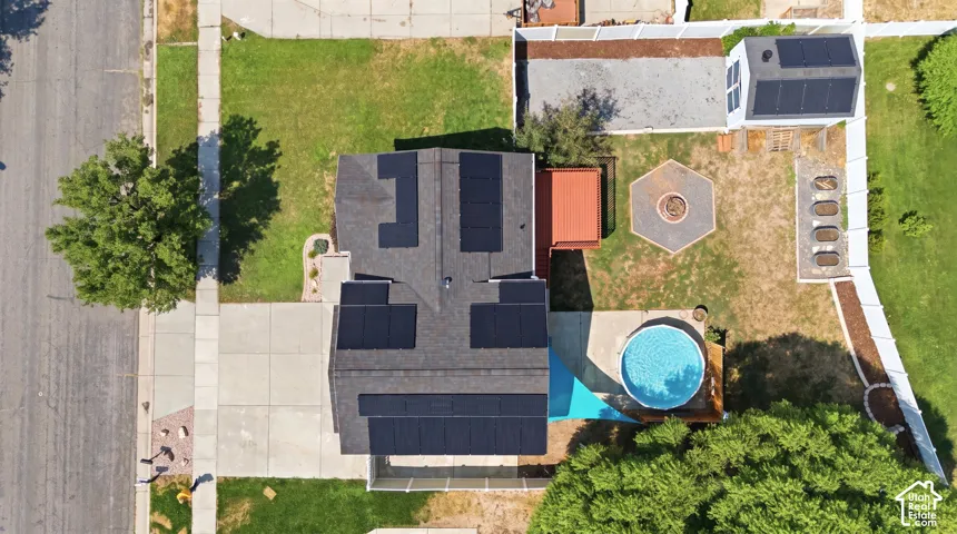 Expansive backyard featuring an above-ground pool, a hexagonal hardscape patio with a fire pit, a raised deck, and a white privacy fence