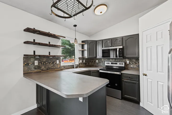 Kitchen featuring dark cabinetry, wood-finish flooring, stainless steel appliances, and open shelving