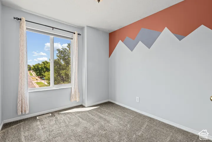 Wall-to-wall carpeting, large window with natural light, decorative accent wall, and ceiling-mounted lighting