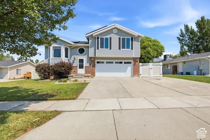 Two-story residence featuring light gray siding, a two-car garage, and a concrete driveway