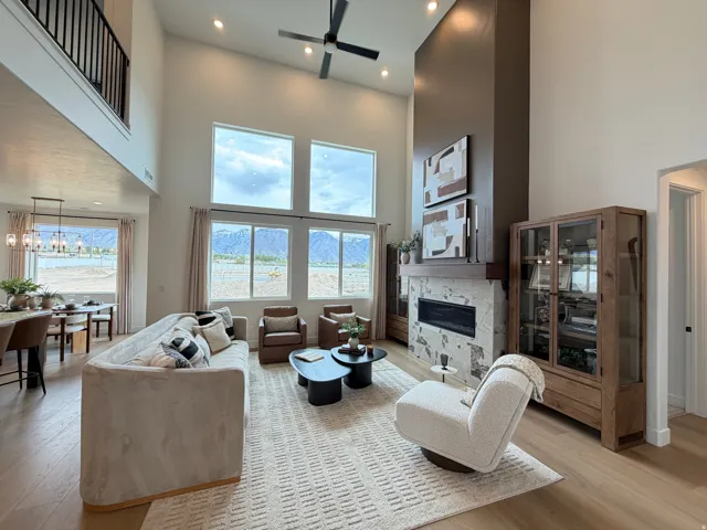Two-story living area with high ceilings, featuring a floor-to-ceiling fireplace with a stone surround and wood mantle