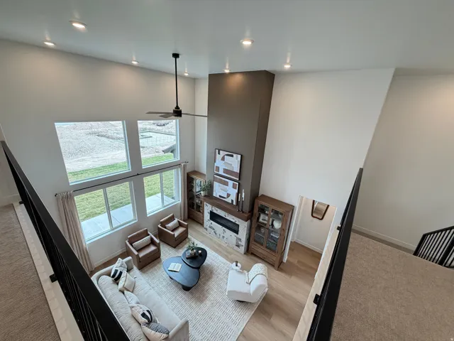 Vaulted living area featuring a two-story fireplace with a stone surround and wood mantel