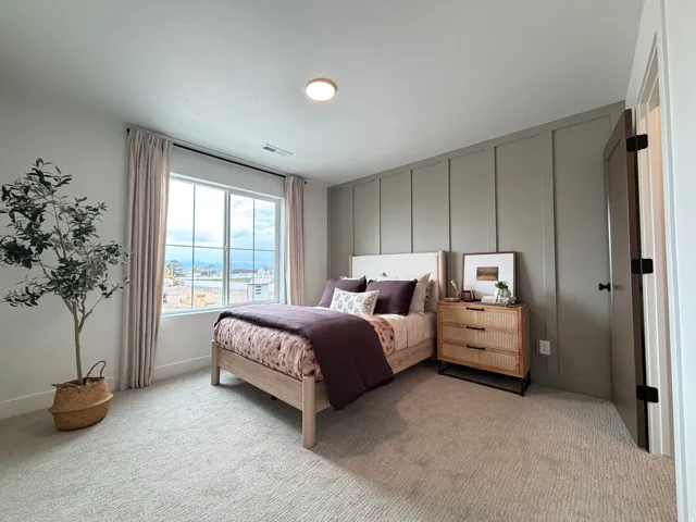 Carpeted bedroom featuring a large window, a board and batten accent wall, and a ceiling-mounted light fixture