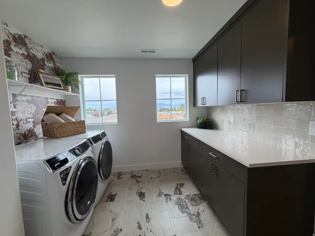 Dedicated utility space featuring sleek dark cabinetry, a spacious countertop, and a tiled backsplash