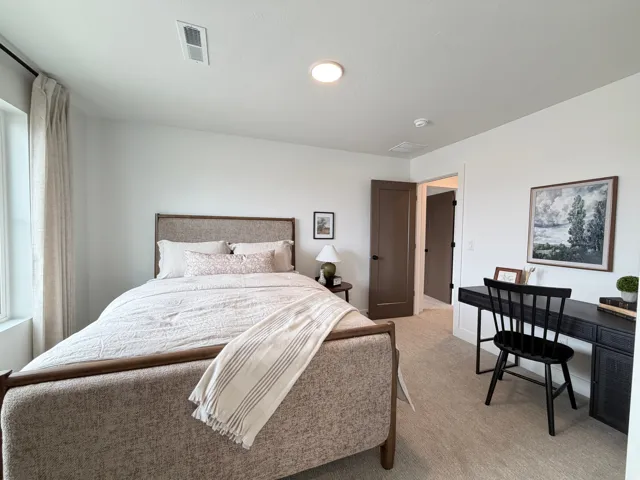 Neutral wall paint and carpeted flooring define this room, featuring a window with a curtain rod and a recessed ceiling light