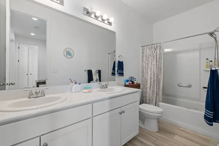 Bathroom featuring a dual vanity with white cabinetry, light countertops, and chrome fixtures