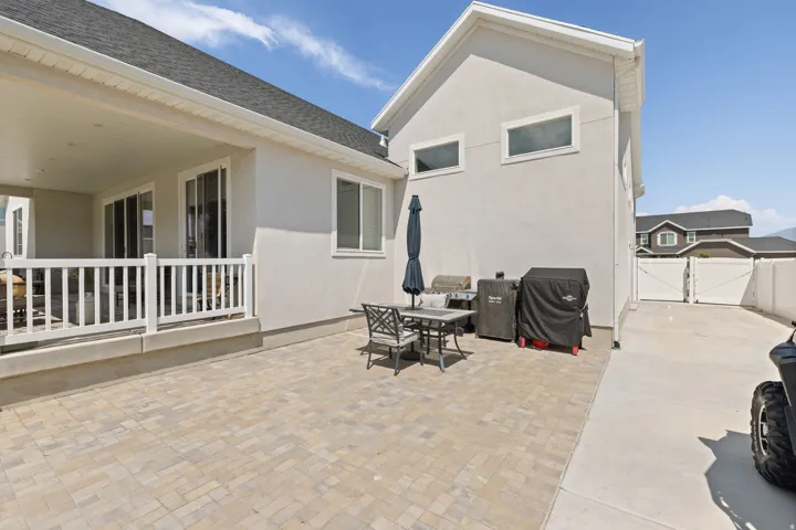 Expansive paver patio with a covered porch featuring white railing