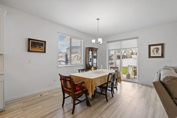 Bright dining area featuring wood-finish flooring, a contemporary chandelier, and a sliding glass door opening to the outdoors