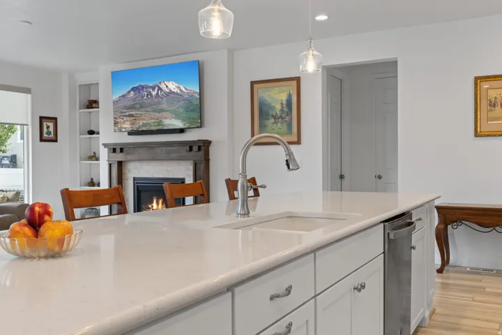 Kitchen island featuring a white countertop with an undermount sink and stainless steel faucet, complemented by white cabinetry and a built-in stainless steel dishwasher
