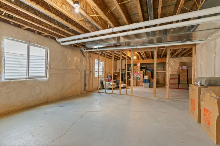 Unfinished basement offering substantial expansion potential, featuring exposed ceiling joists, concrete flooring, and multiple framed interior walls
