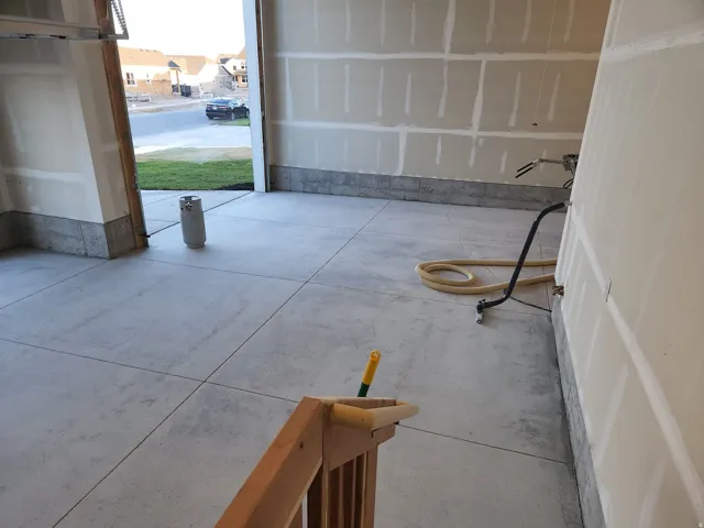 Spacious garage featuring a concrete floor, framed garage door opening, and unfinished drywall
