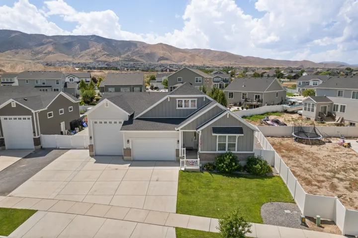 Contemporary residence featuring a two-car garage, partial stone facade, and a manicured front lawn