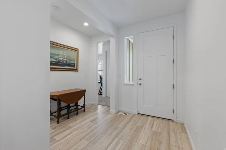 Entryway featuring wood-finish tile flooring, recessed lighting, and a solid white entry door with frosted glass sidelight