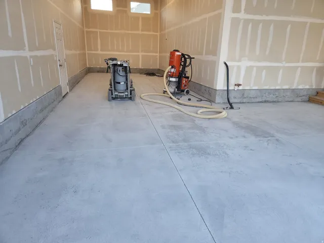 Spacious garage interior featuring concrete flooring, unpainted drywall, and high-set windows providing natural light