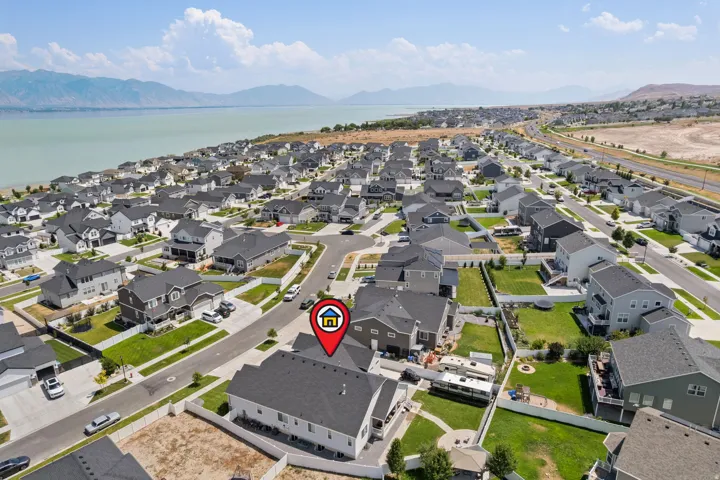 Aerial perspective of a developed residential community featuring numerous single-family homes with dark-pitched roofs and light-colored siding