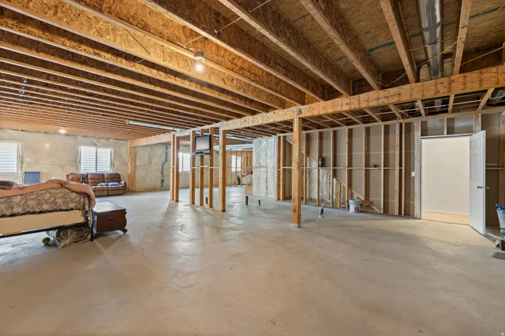 Unfinished lower level featuring exposed wood joists and concrete flooring
