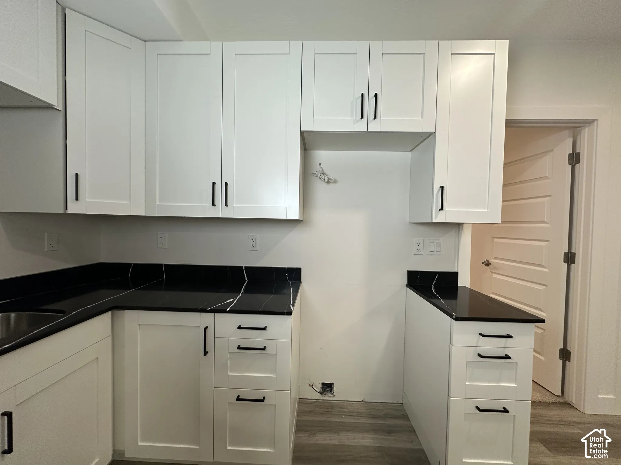 Modern kitchen area featuring crisp white shaker-style cabinetry with matte black hardware
