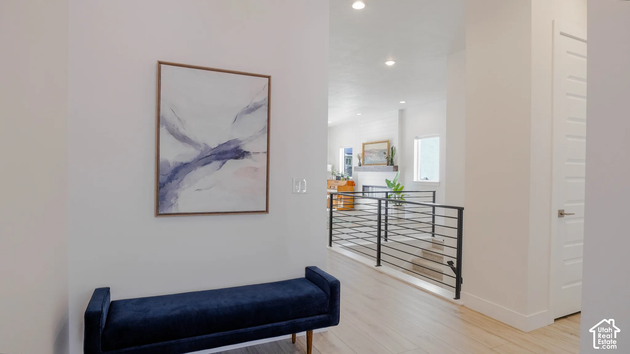 Light wood-finish flooring extending into an open living area featuring recessed lighting, a fireplace with mantel, and a multi-pane window