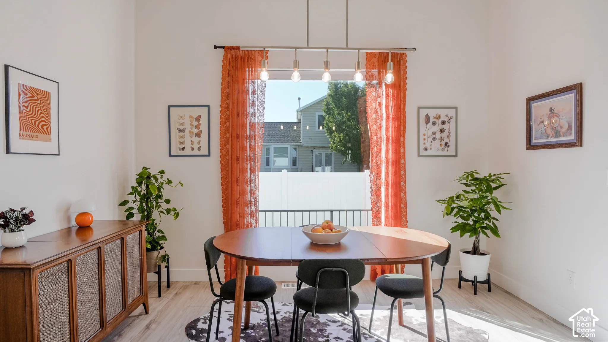 Dining area featuring a large window, a linear pendant light fixture, light wood-finish flooring, and white painted walls