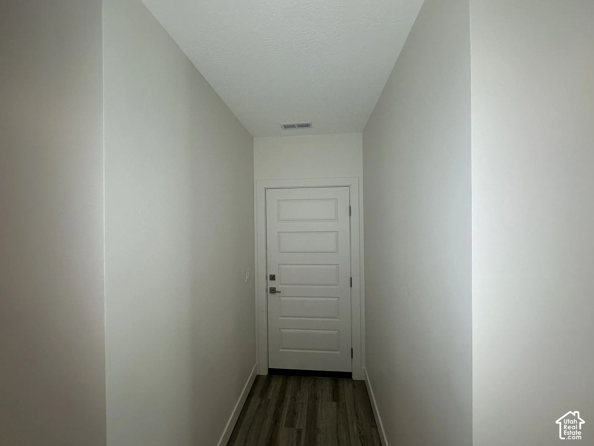 Hallway featuring white painted walls and wood-finish flooring
