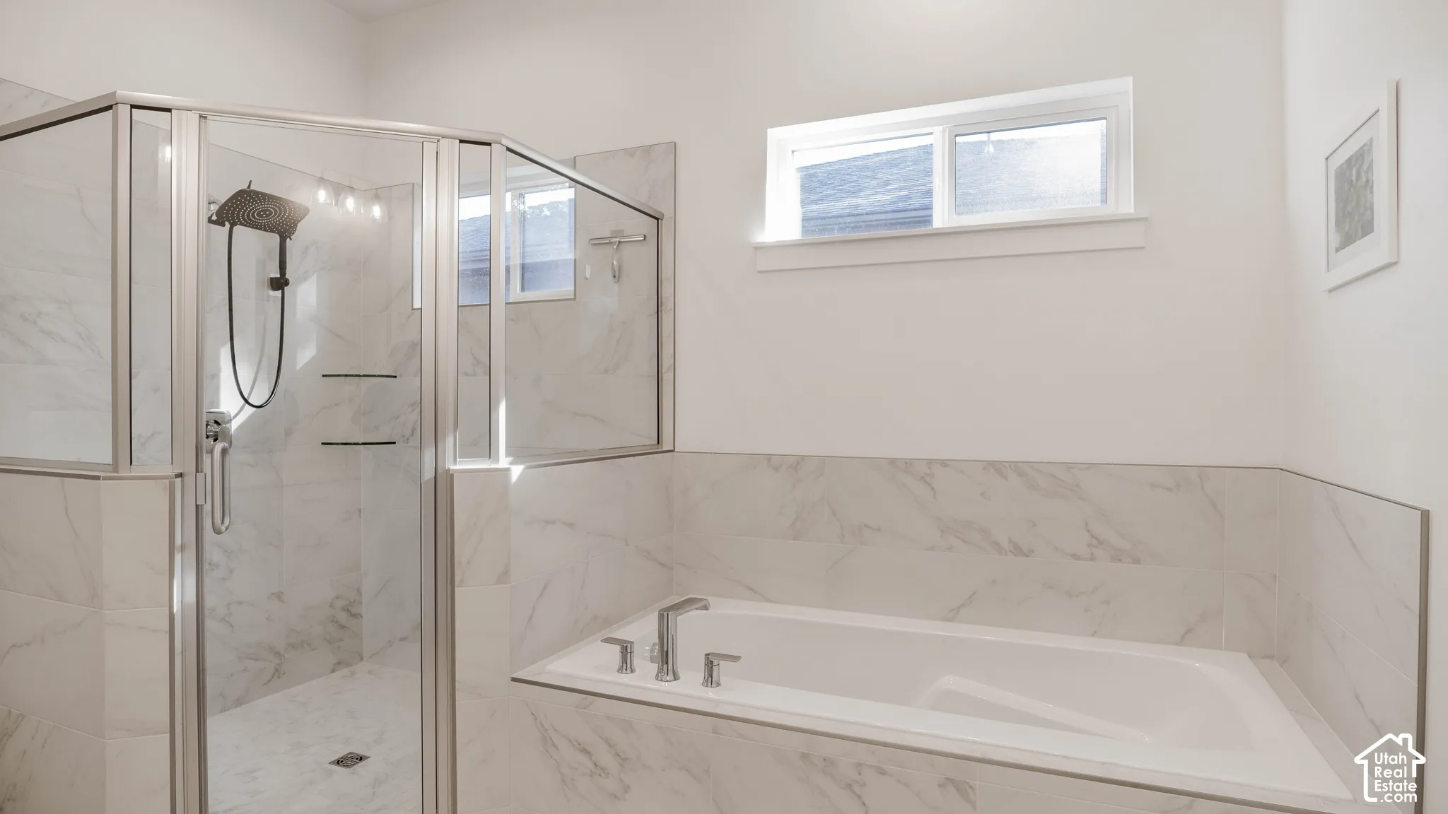 Bright bathroom featuring a spacious walk-in shower with glass enclosure, an integrated bathtub, and white marble-look tile surrounds
