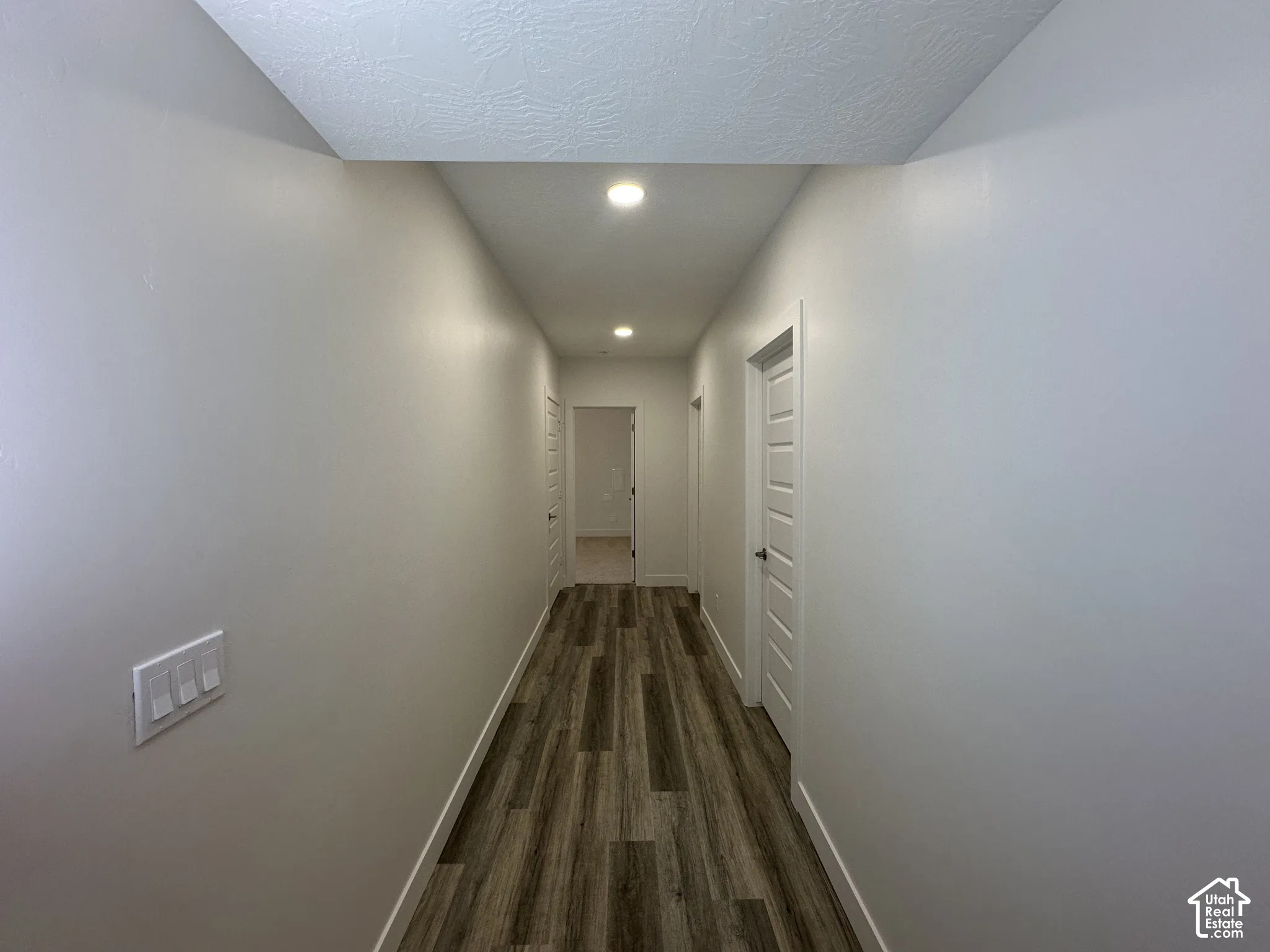Hallway featuring recessed lighting, wood-finish flooring throughout, and clean white walls with modern white panel doors
