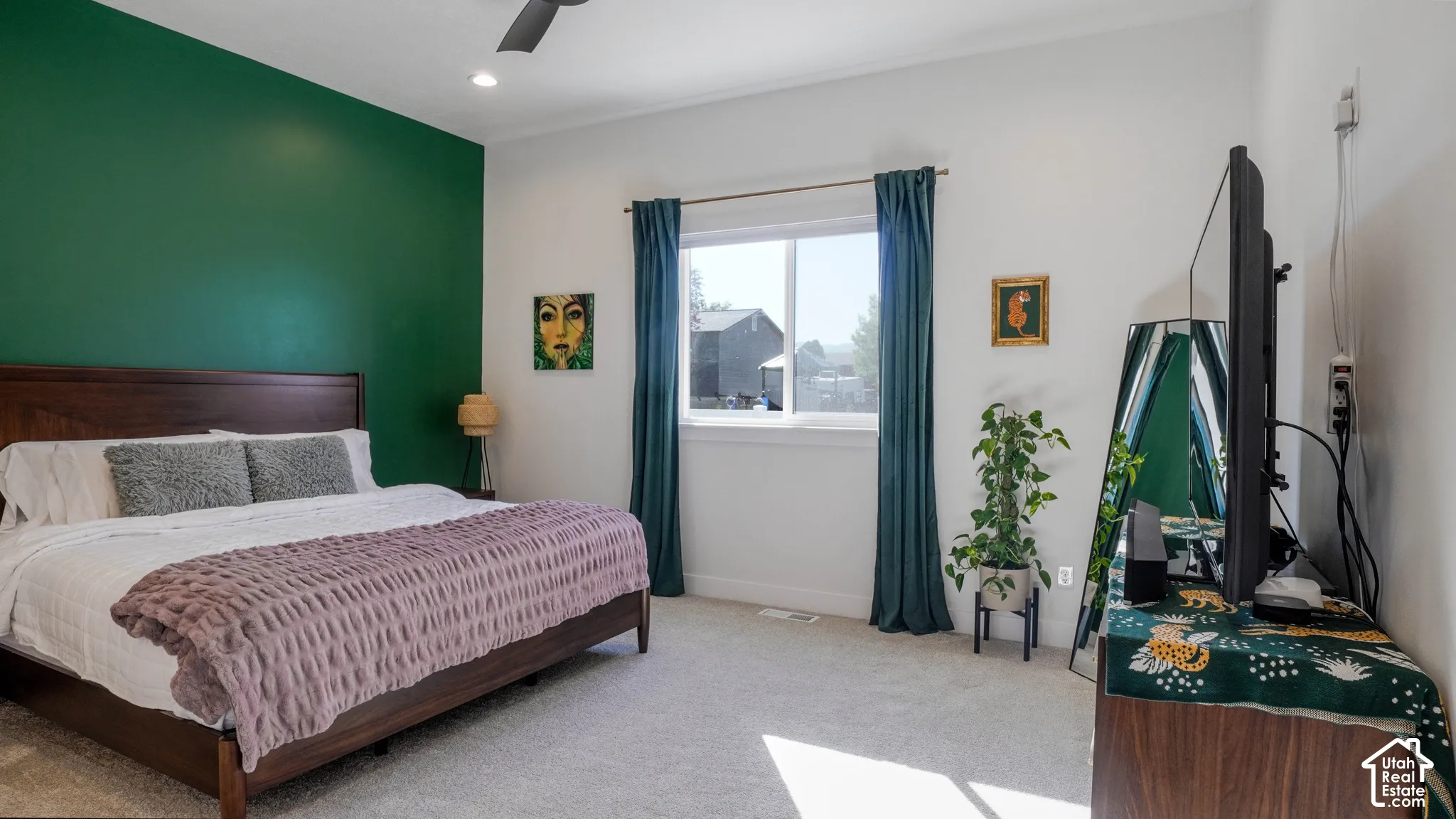 Carpeted room featuring a window with teal drapes, a dark wood-finish bed frame, and a contrasting green accent wall