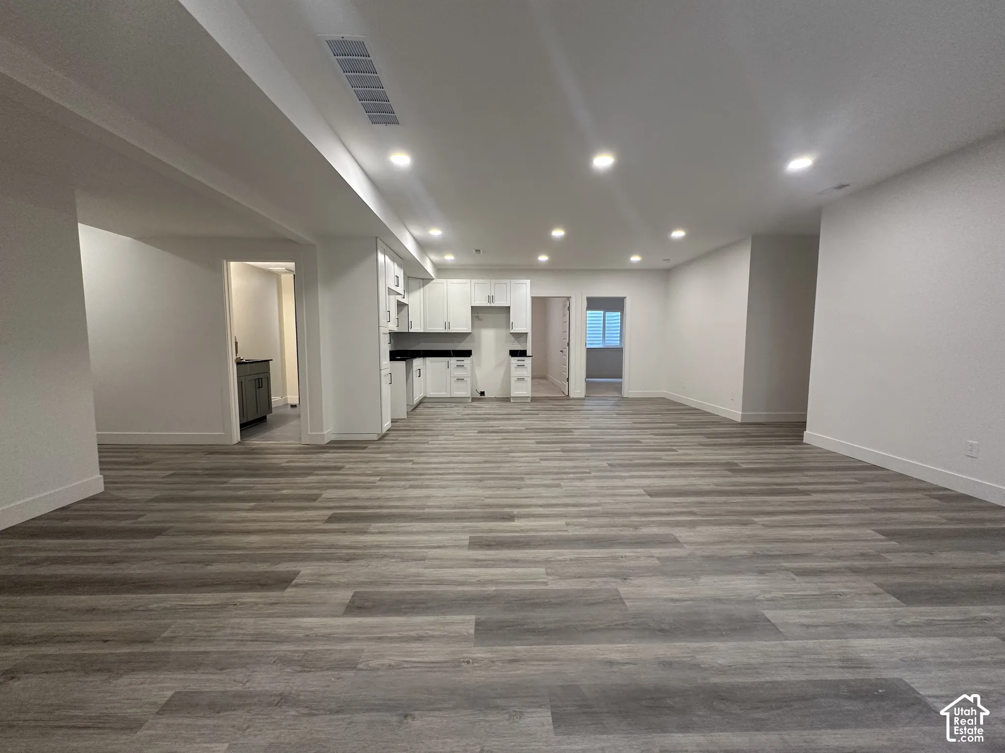 Open-concept living space featuring wood-finish flooring, recessed lighting, and white walls