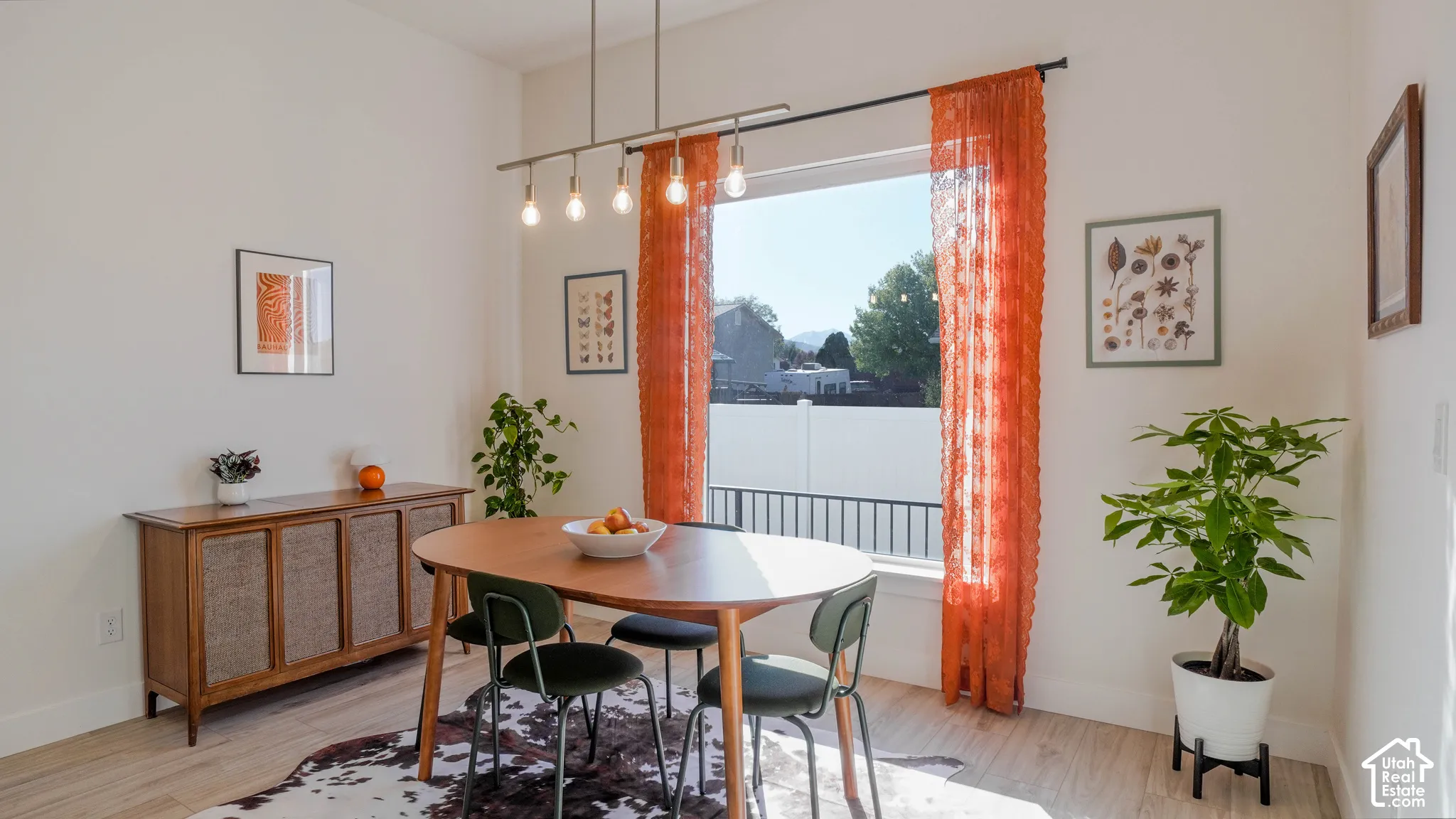 Bright dining area featuring a large window, a linear pendant light fixture, and light wood-finish flooring