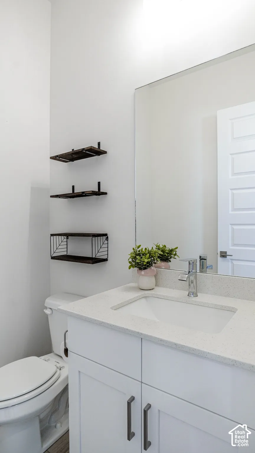Bathroom vanity featuring a white countertop with integrated sink, chrome faucet, and white shaker-style cabinetry with dark hardware